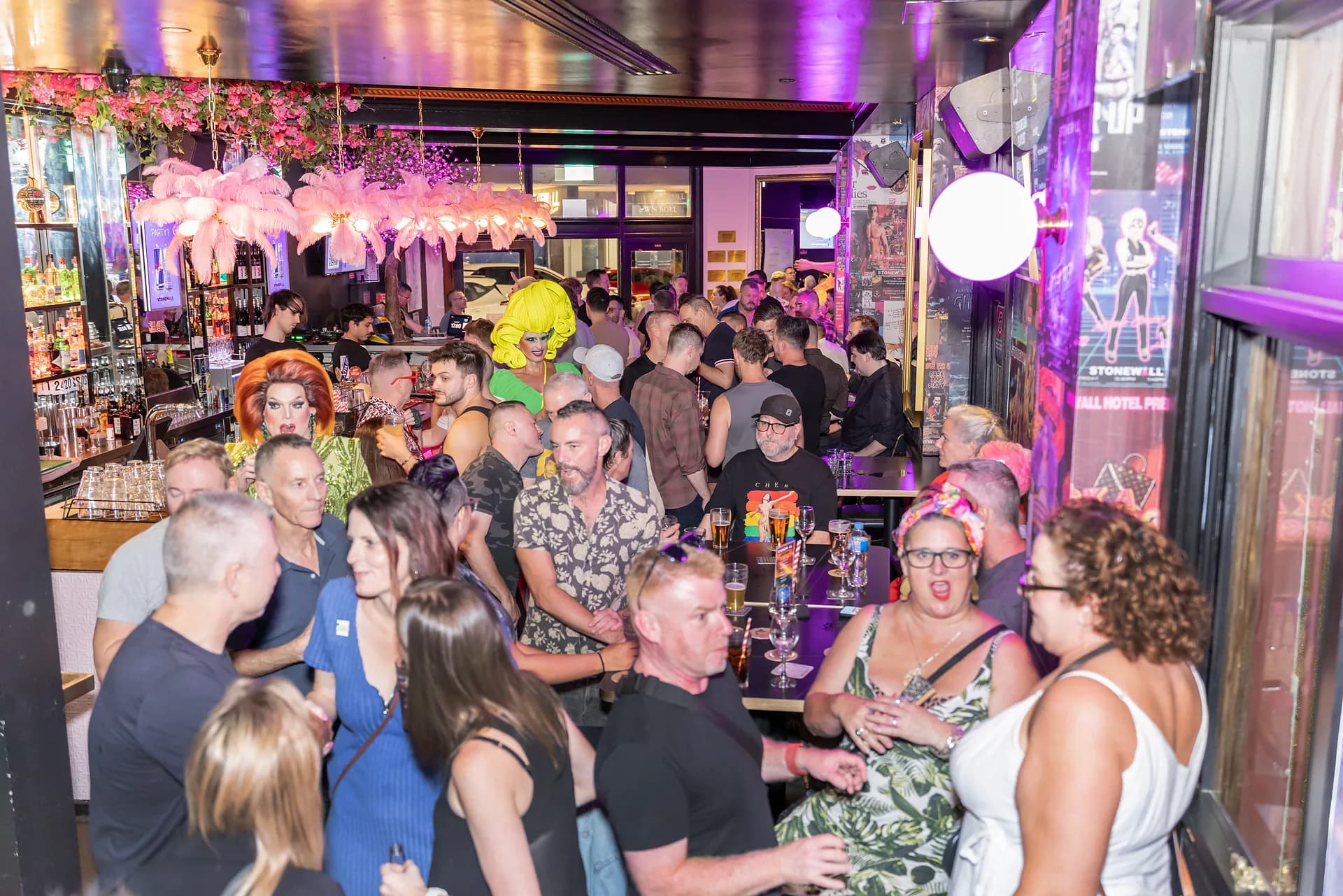A launch-night crowd filling Stonewall Newtown's main bar beneath pink feather lights.